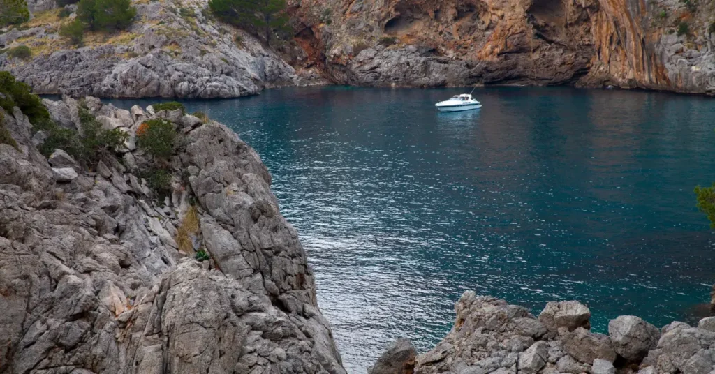 A boat in the waters of Sa Calobra Mallorca The rocky shoreline